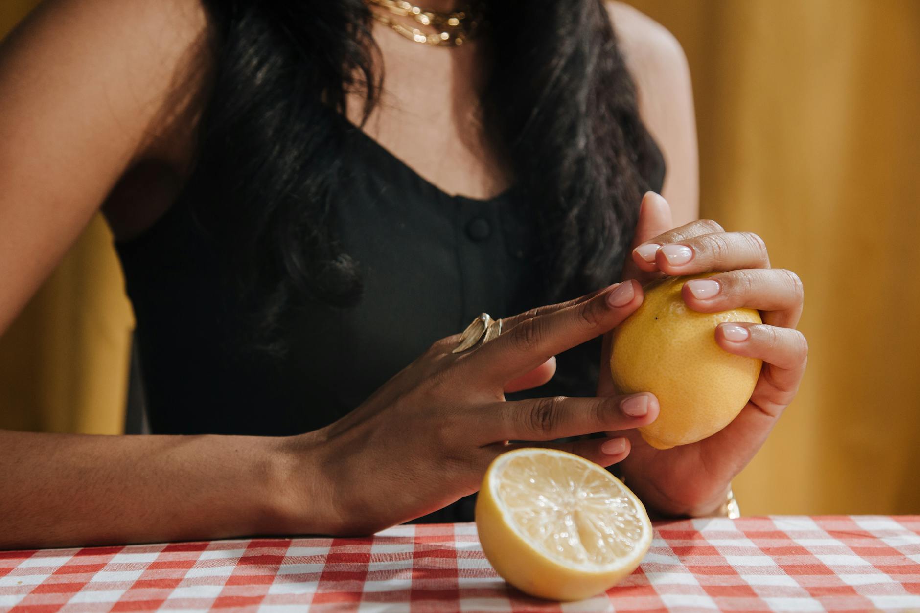 Close-up of a woman holding a fresh lemon at a dining table
