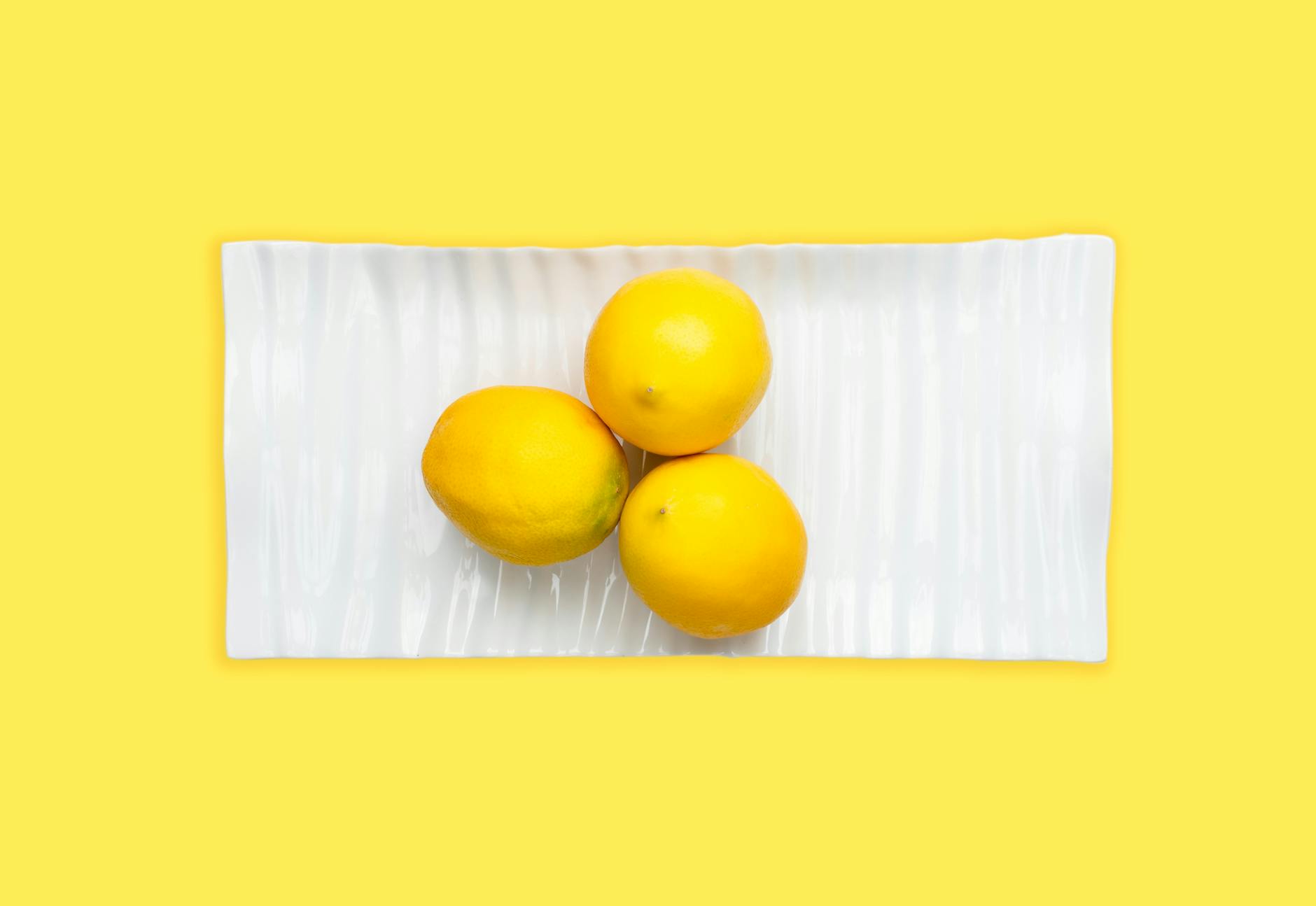 Fresh lemons on a white plate with yellow background, symbolizing renewal and gentle reintroduction to sensation